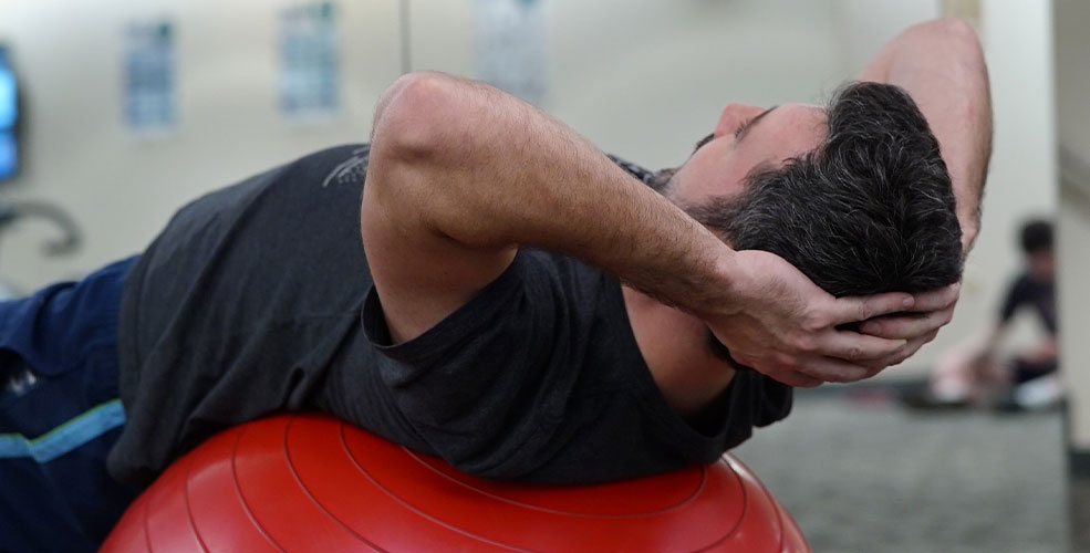 Mand der laver push-ups liggende på ryggen på en rød pilatesbold